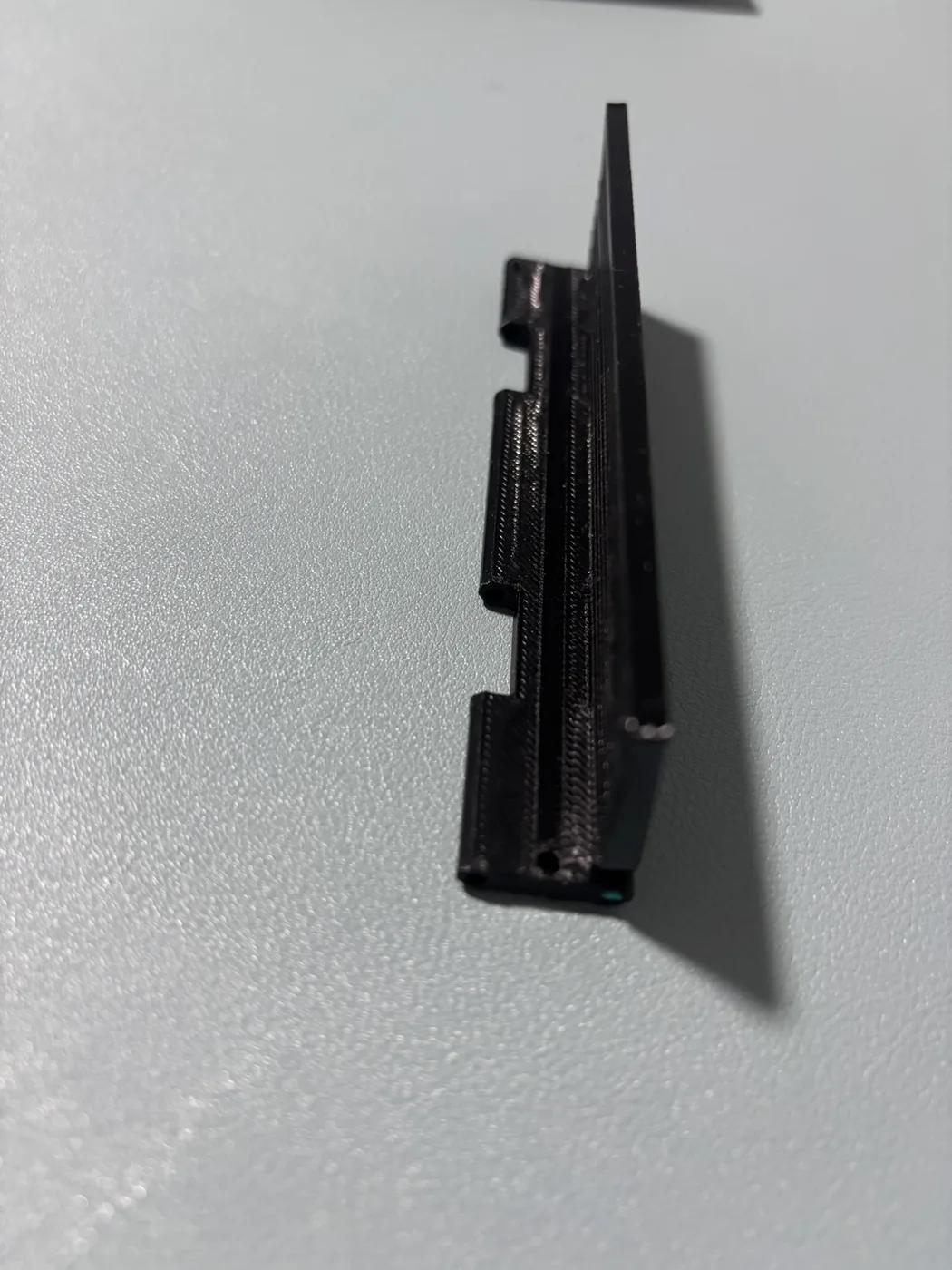 Black printed hinge sample with its cover-edge strip raised.